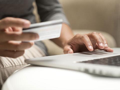 Person using a laptop and checking credit card